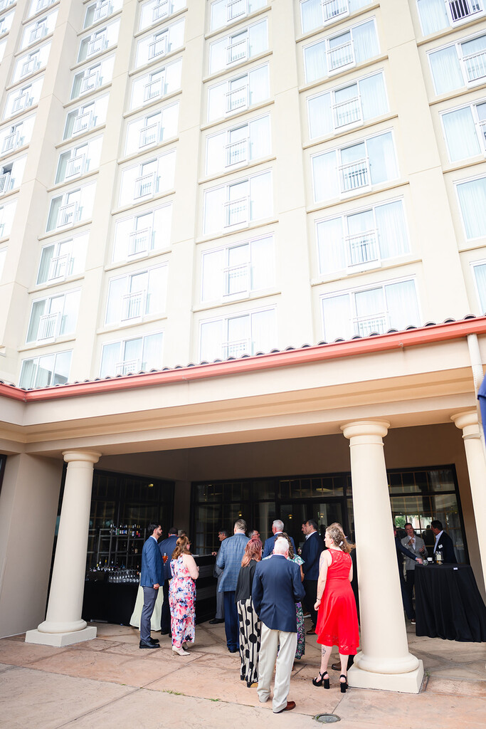 Guests networking under the columned patio of the Myrtle Beach Marriott Resort as the tan hotel rises behind them