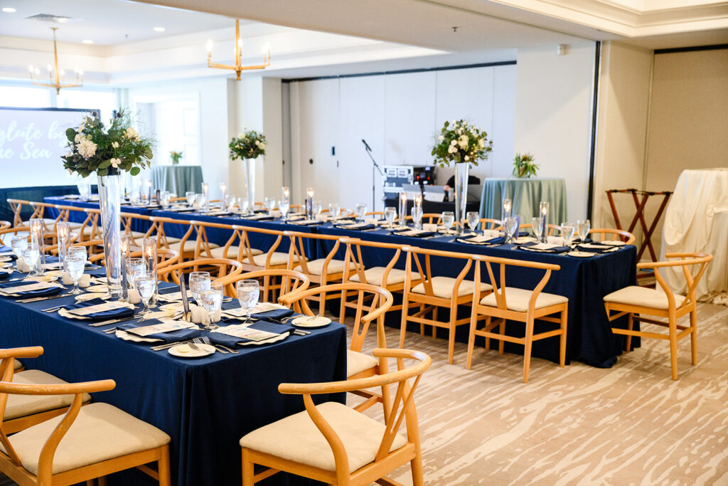 Banquet hall set with navy linens, gold chairs, and tall florals at Dunes Club
