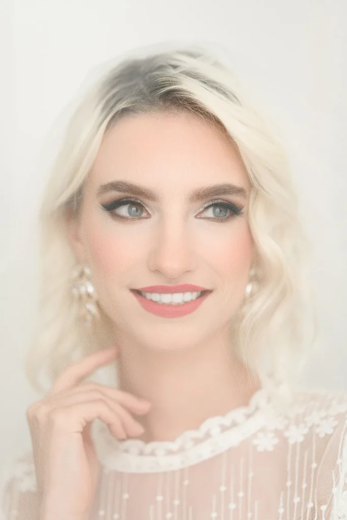 Close-up bridal portrait with soft makeup, an updo, and pearl drop earrings