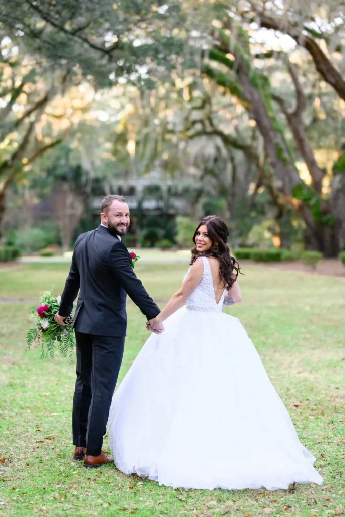 Bride and groom holding hands under oak trees at golden hour