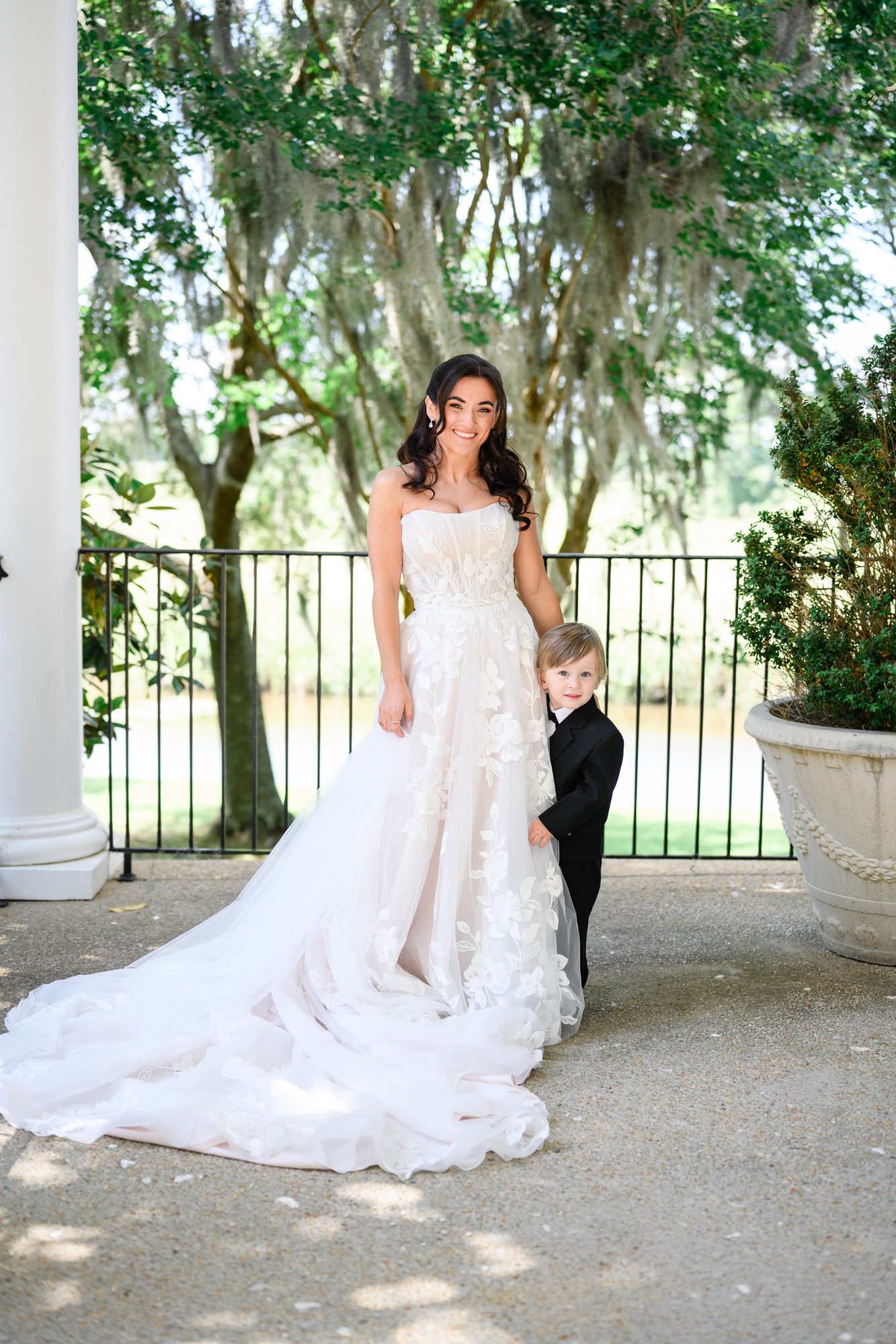 Ally in her lace gown with the young ring bearer on the porch at Caledonia Golf & Fish Club