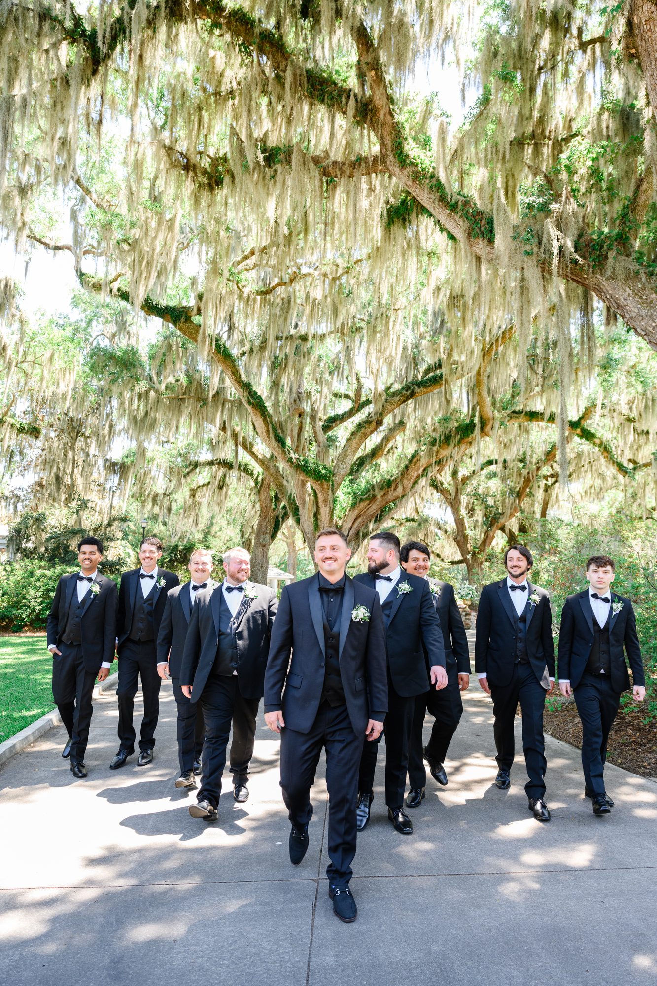 Patrick and his groomsmen walking down an oak-lined path at Caledonia