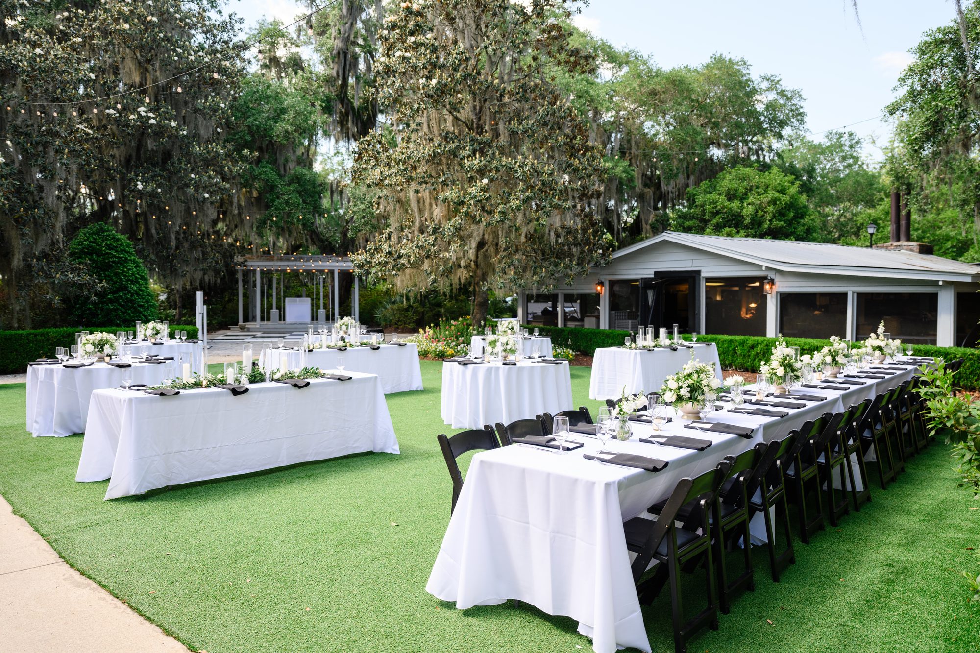 Long reception tables set on the lawn among the trees at Caledonia Golf & Fish Club