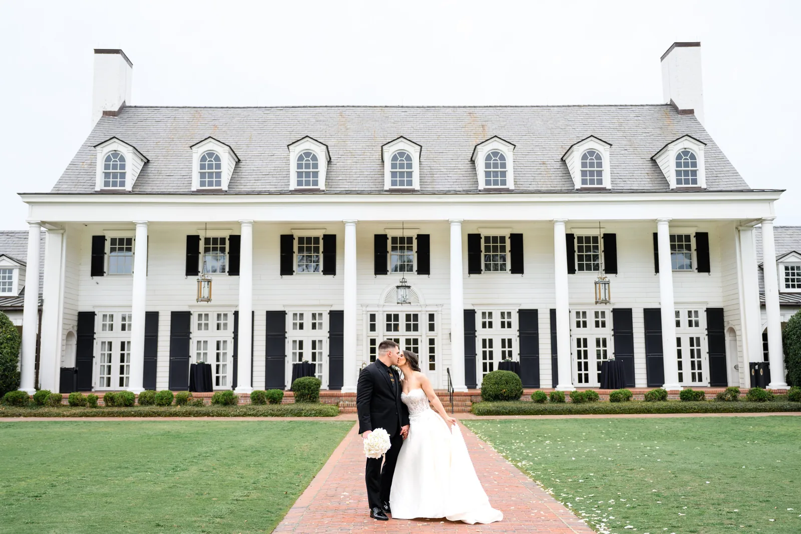 Kayla and Austin in front of the white-columned Pine Lakes Country Club clubhouse