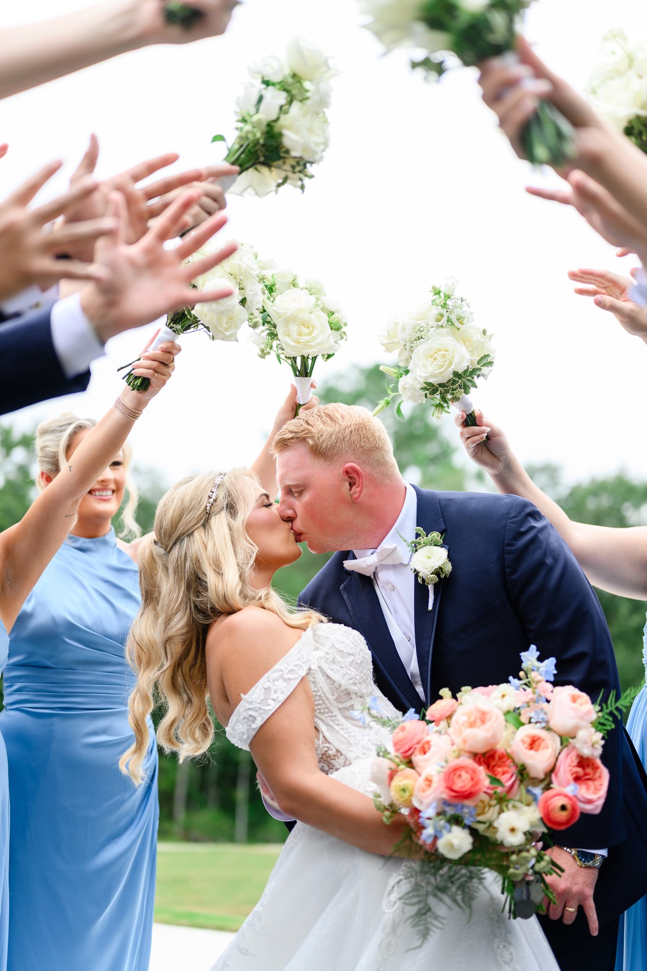 Bride and groom kiss beneath bridesmaids' raised bouquets at a Myrtle Beach wedding