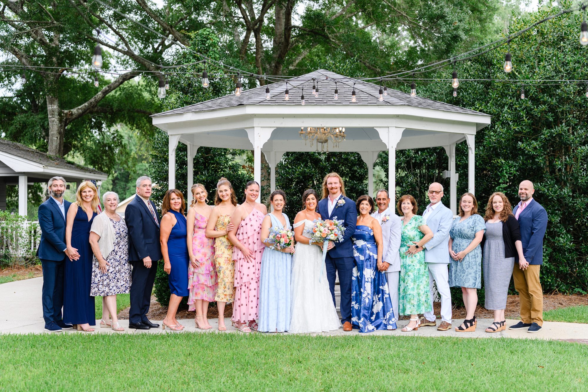 Elesabeth and Luke with family in front of the white gazebo at The Village House