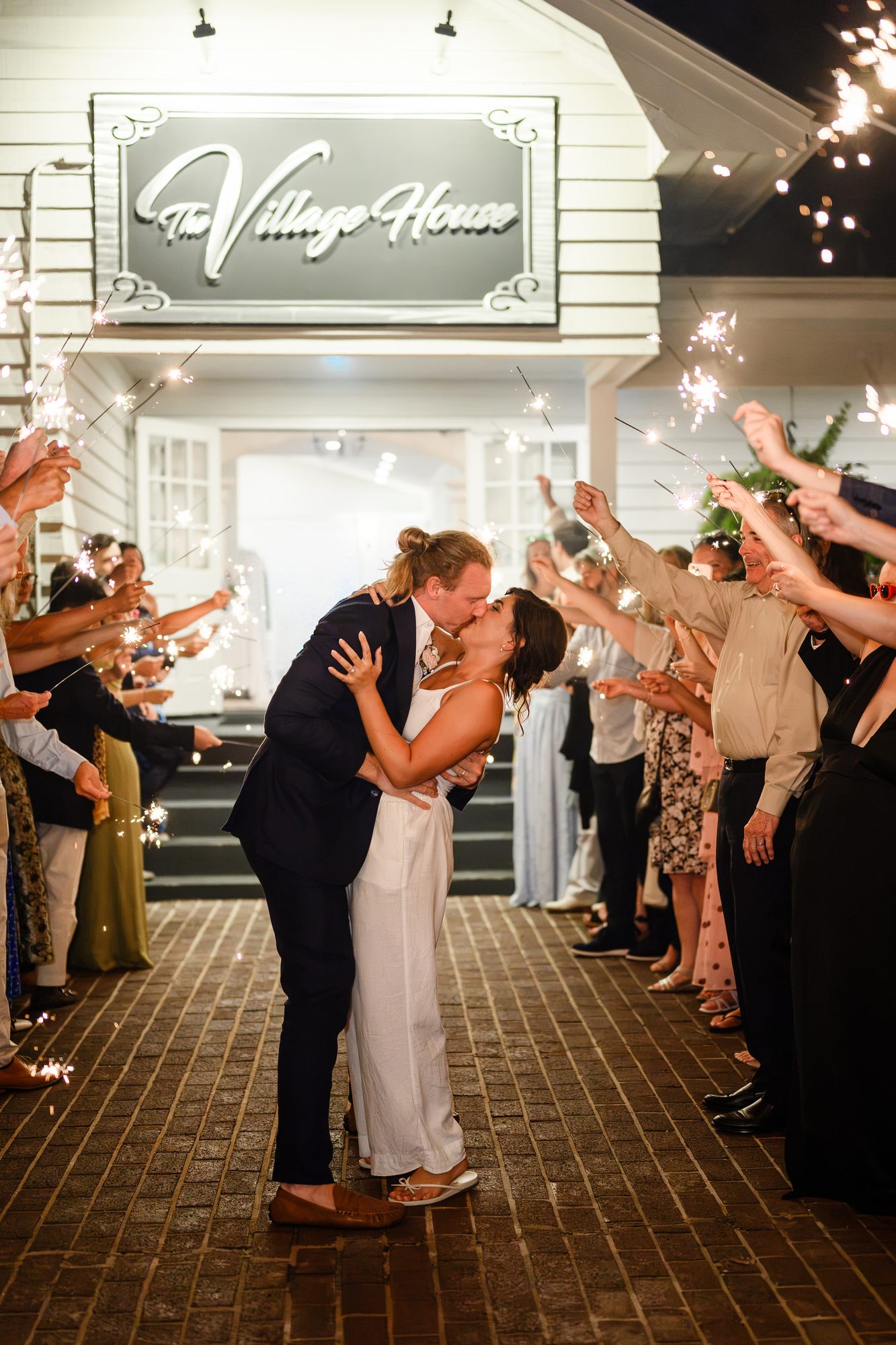 Elesabeth and Luke kissing during their sparkler send-off outside The Village House