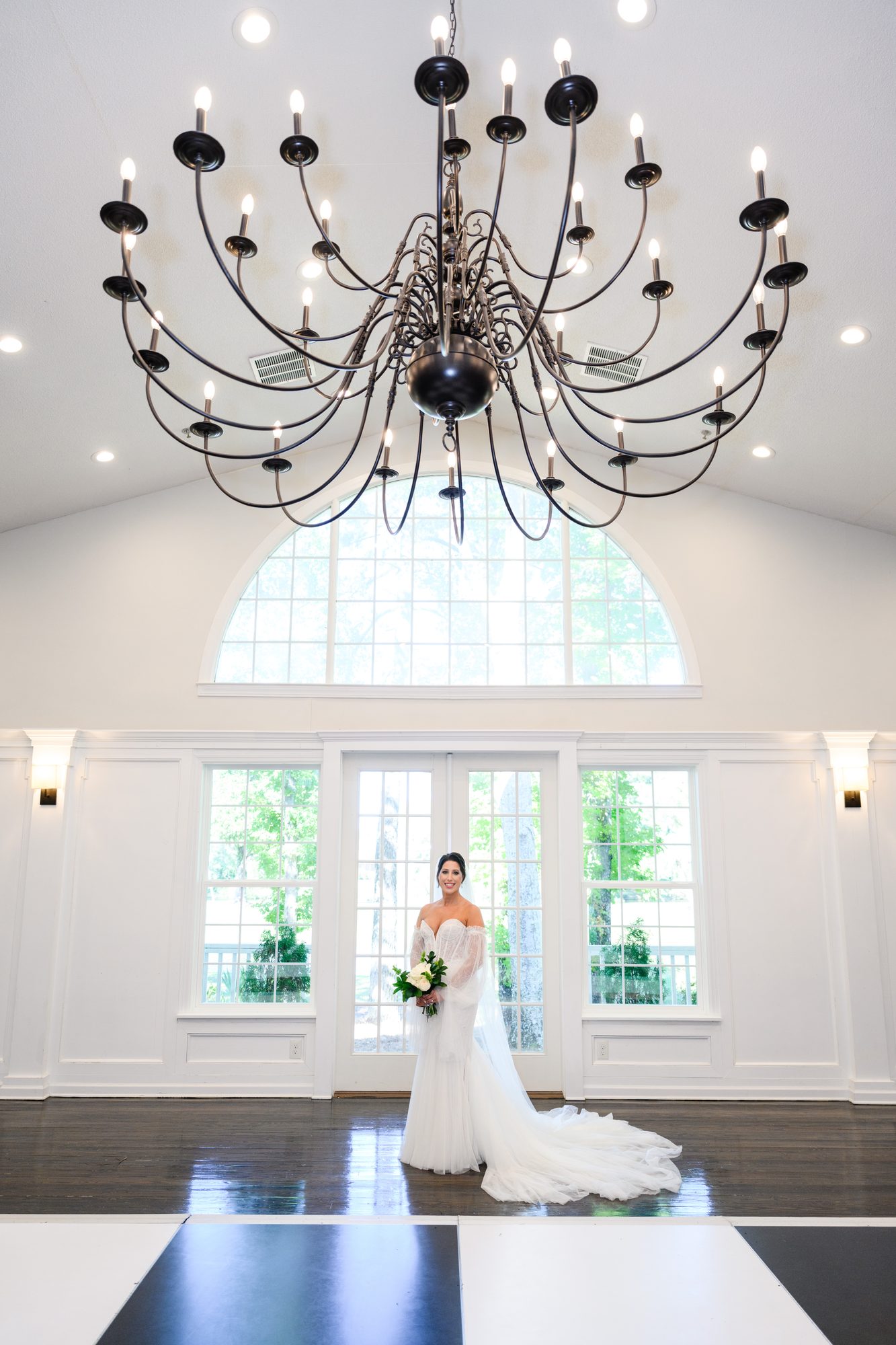Shannon standing beneath a wrought-iron chandelier inside The Village House at Litchfield