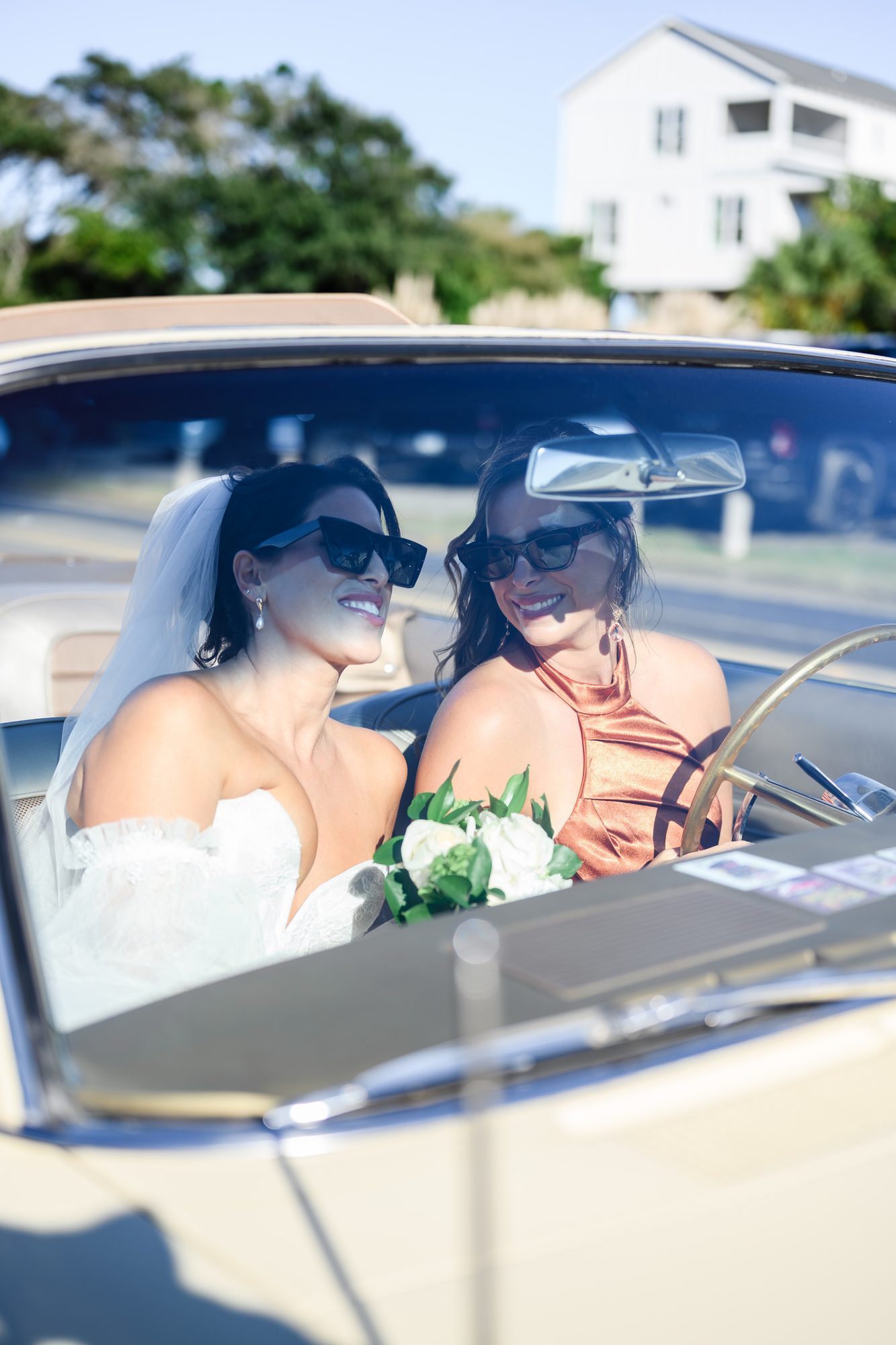 Shannon and a friend in sunglasses riding in a vintage white convertible in Pawleys Island