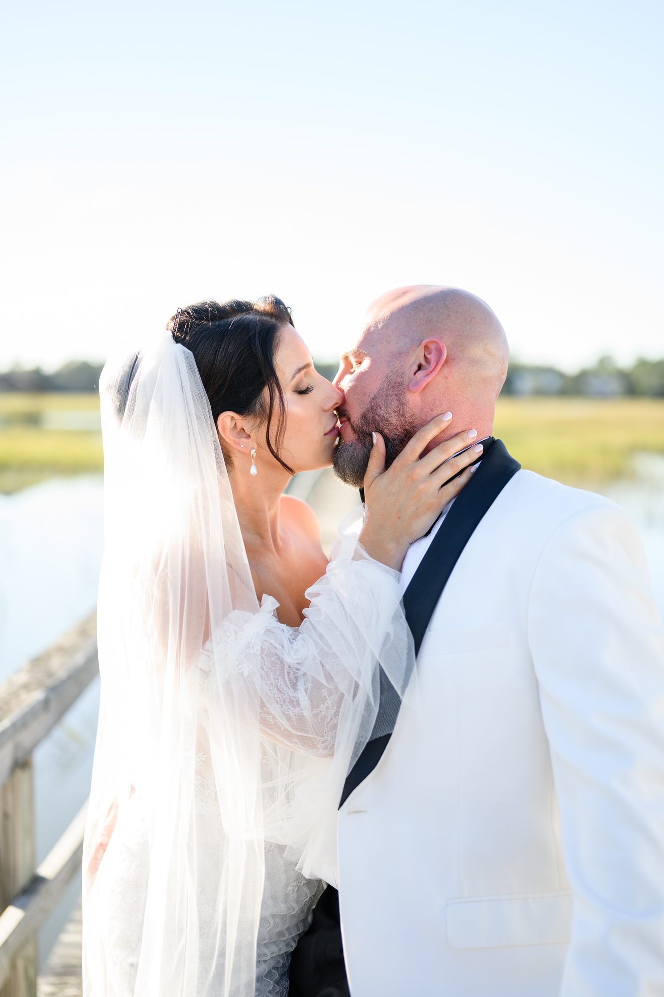 Shannon and Eddie kissing beside the marsh at golden hour in Pawleys Island