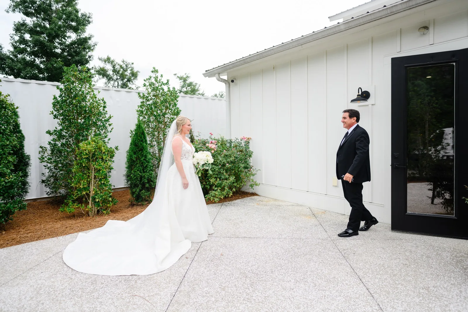 Bride walks toward her father for a first look just outside the venue at White Oaks Farm